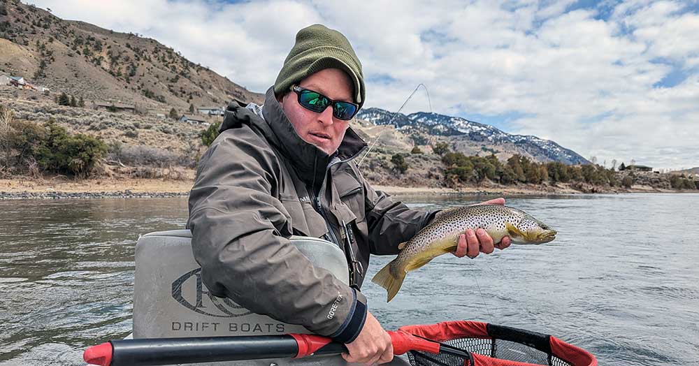 Angler holding brown trout. Snow in background.