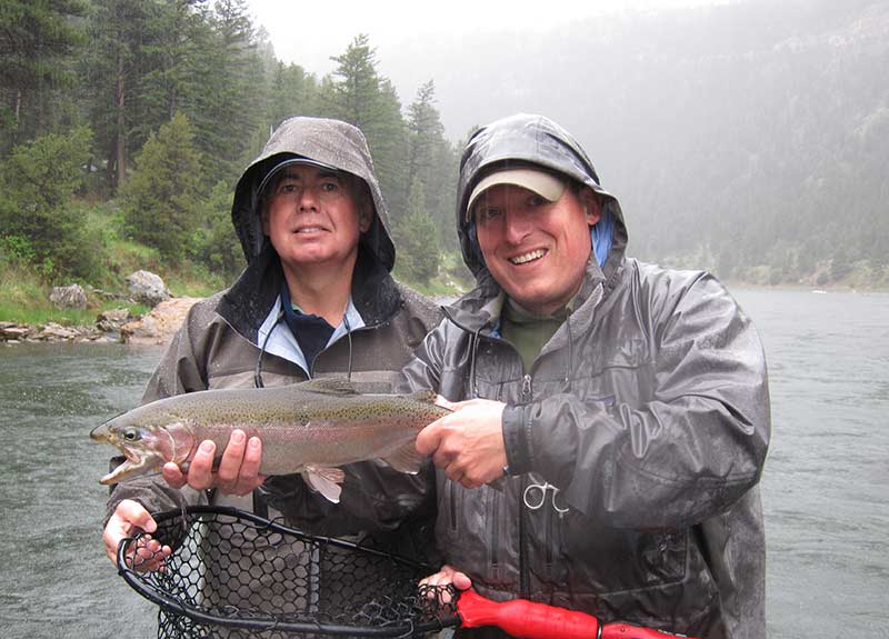 cold wet angler and guide with large rainbow trout