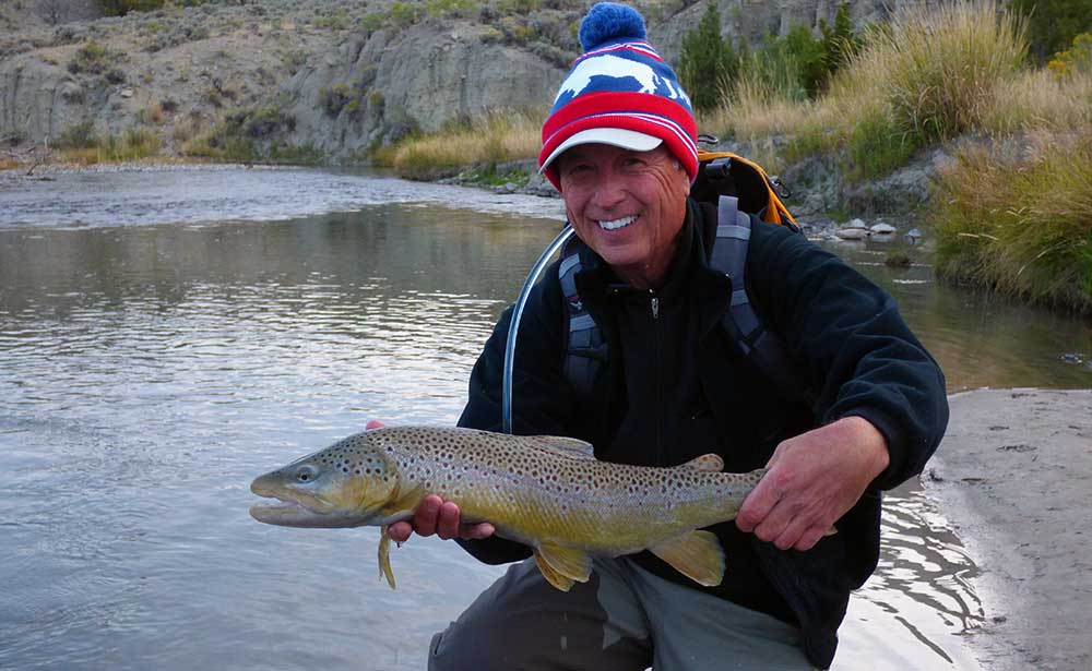 Smiling angler with large brown trout caught on a Yellowstone Park walk and wade trip