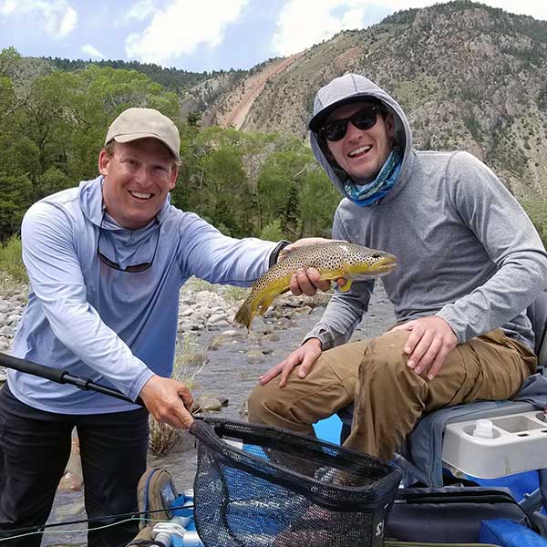 angler, guide, and trout, with Devil's Slide in background