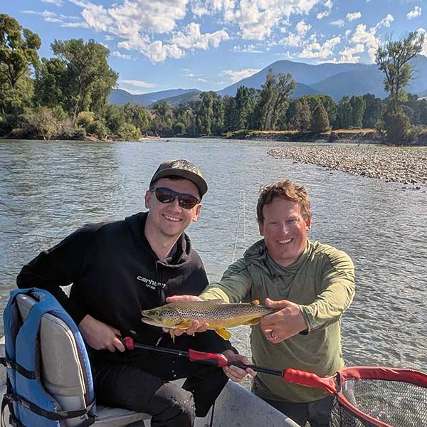 angler, guide, brown trout, with pretty mountain and river scenery in background